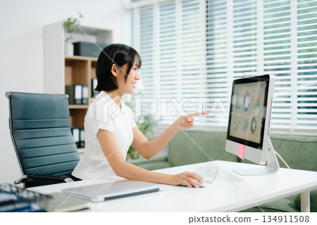 A focused office woman writing notes and working on paperwork at her desk, representing productivity, organization, business tasks, A focused office woman writing notes and working on paperwork at her desk, representing productivity, organization, business tasks, 134911508