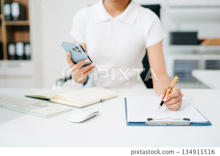 Confident businessman working on laptop, tablet and smartphone at her workplace at modern office. 134911516