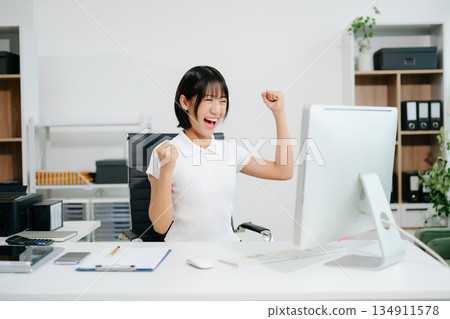 Asian business woman are delighted and happy with the work they do on their tablet, laptop and taking notes at the office. 134911578