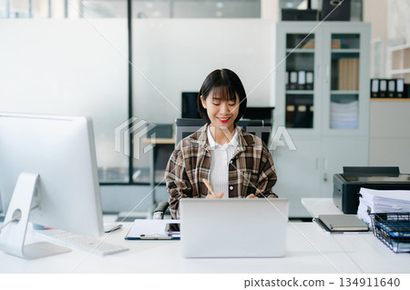 Business woman using tablet and laptop for doing math finance on an office desk, tax, report, accounting, statistics, and analytical research concept in office Business woman using tablet and laptop for doing math finance on an office desk, tax, report, accounting, statistics, and analytical research concept in office 134911640