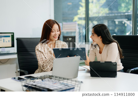 Businesswomen work and discuss their business plans. A woman employee explains and shows her colleague 134911800