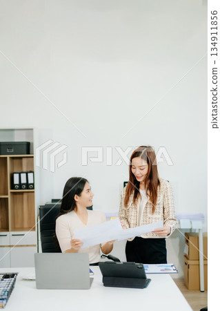 Two Asian businesswomen working together on a digital tablet in office. Perfect for themes of teamwork 134911856