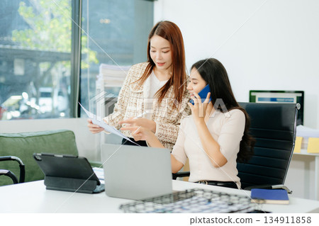 Two Asian businesswomen working together on a digital tablet in office. Perfect for themes of teamwork 134911858