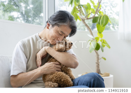 A man in his 50s holding a toy poodle - image of life with a dog 134911910