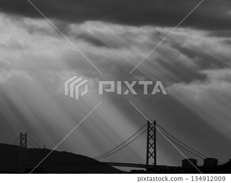 一座巨大的懸索橋,陽光透過雲層灑下斑駁的光影。 一座巨大的懸索橋,陽光透過雲層灑下斑駁的光影。 134912009