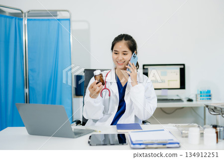 Confident young female doctor in white medical uniform sit at desk working on computer. Confident young female doctor in white medical uniform sit at desk working on computer. 134912251