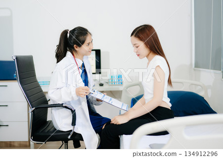 Asian female doctor explains diagnosis with compassion during a medical consultation. Perfect for healthcare, trust, patient care 134912296