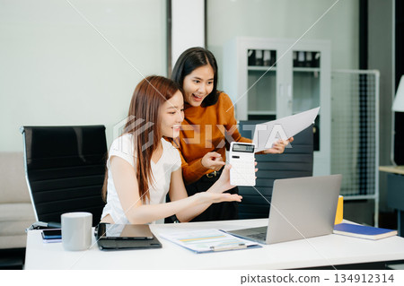 Businesswomen work and discuss their business plans. A woman employee explains and shows her colleague 134912314