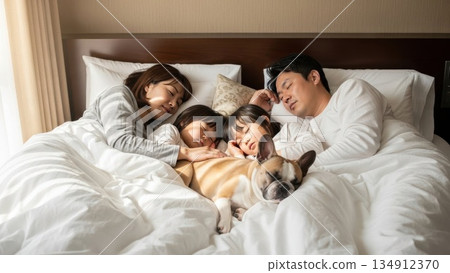 清晨的陽光下，父母、孩子和寵物狗一起睡著了。 134912370