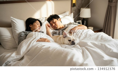 在清晨的陽光下，一對年輕夫婦和他們的狗依偎在一起，安詳地睡著了。 134912376