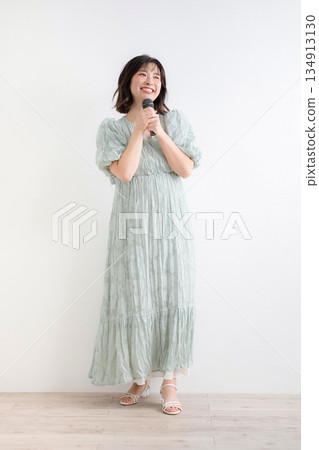 一位女士手持麥克風，正在嘗試聲樂課程和歌唱訓練。圖片展示了上課和主持的場景。 134913130