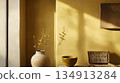 A vase with flowers sits on a table in front of a yellow wall 134913284