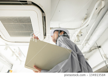 Woman checking the air conditioner Woman checking the air conditioner 134913584