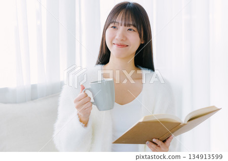 Young woman reading in living room Young woman reading in living room 134913599