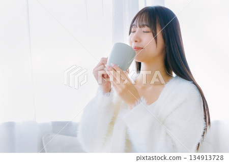 年輕女子在客廳裡喝咖啡 年輕女子在客廳裡喝咖啡 134913728