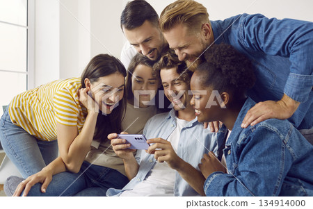 Group shot of happy diverse friends watching something on mobile phone all together Group shot of happy diverse friends watching something on mobile phone all together 134914000