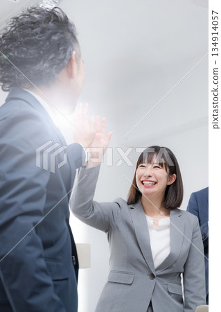 Businessmen high-fiving, woman and boss, business scene of success and achievement, vertical 134914057
