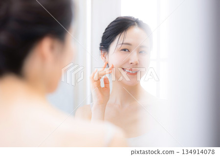 A woman looking in the mirror, moisturizing and skin care 134914078