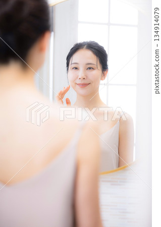 A woman looking in the mirror, moisturizing and skin care 134914079