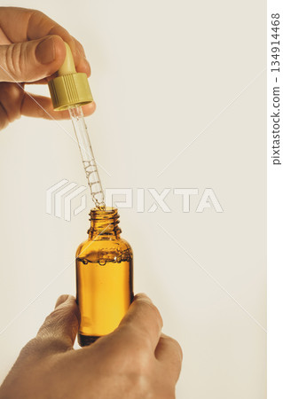Hand holding and preparing an essential oil dropper bottle with natural liquid 134914468