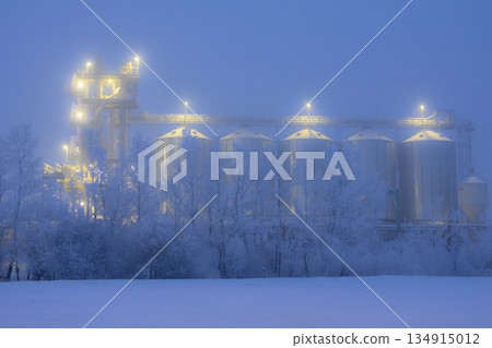 Lights on grain elevator storage in foggy winter night. 134915012