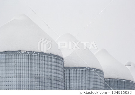 Monochrome of steel grain bins covered with snow after snowfall. Monochrome of steel grain bins covered with snow after snowfall. 134915023