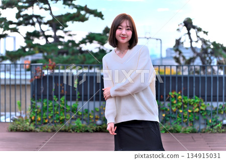 A woman in a white knitted sweater looking relaxed on an outdoor terrace 134915031