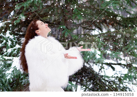 Woman in a white fur coat in the snowy winter forest. 134915058