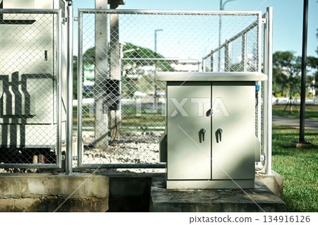 Outdoor electrical control cabinet inside fenced utility area in public park 134916126