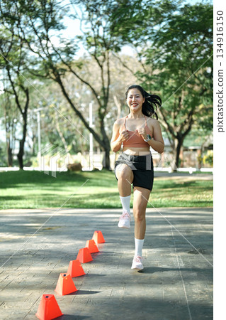 Woman doing speed and agility cone drills workout session outdoors 134916150