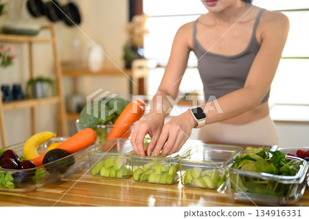 Closeup of a woman hand placing freshly cut fruits and vegetables into food storage containers, meal prep, and food preservation Closeup of a woman hand placing freshly cut fruits and vegetables into food storage containers, meal prep, and food preservation 134916331