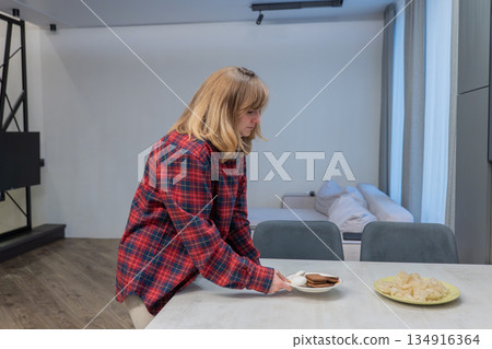 Woman ponders breakfast, Freelancer woman carefully considers her breakfast options before beginning work, Creative professional woman takes brief moment to choose her breakfast plate thoughtfully 134916364