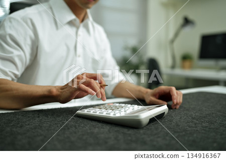 Closeup Business finance accounting banking concept. Businessman doing finances, using calculator to calculate business report on desk at office Closeup Business finance accounting banking concept. Businessman doing finances, using calculator to calculate business report on desk at office 134916367