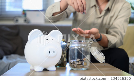 Piggy bank savings with a man holding a coin Piggy bank savings with a man holding a coin 134916390