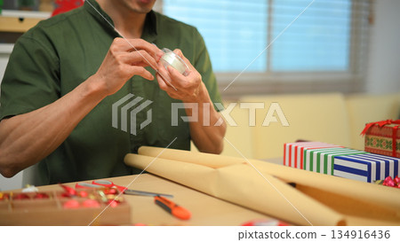Photo set Man wrapping Christmas gifts at home with scissors and festive decorations Photo set Man wrapping Christmas gifts at home with scissors and festive decorations 134916436