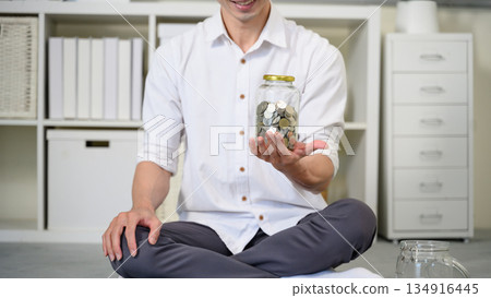 Closeup man holding jar of coin, Saving concept 134916445