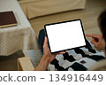 Close up view of a man using blank screen digital tablet on armchair 134916449