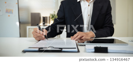 Closeup image businessman sitting at desk signing contract Closeup image businessman sitting at desk signing contract 134916467