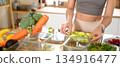 Closeup of a woman hand placing freshly cut fruits and vegetables into food storage containers, meal prep, and food preservation 134916477