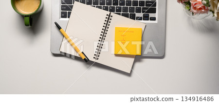 business concept. top view of office desk workspace with, pen, laptop, flower and hot coffee cup on white table business concept. top view of office desk workspace with, pen, laptop, flower and hot coffee cup on white table 134916486