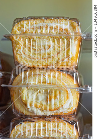 Fresh sweet pastries in a transparent container stand on the shelves of a grocery store 134916894