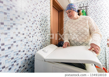 Loading vertical washing machine with laundry housewife closes lid with locking mechanism. Loading vertical washing machine with laundry housewife closes lid with locking mechanism. 134918010