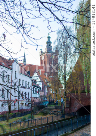 Historic building and tower near a river in a city with trees in winter 134918141