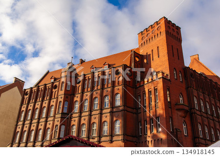 Historic red brick building with tall tower under cloudy sky in Gdansk, Poland 134918145
