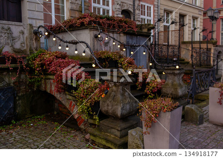 Vines grow on a stone wall with lights at an old building in fall season 134918177