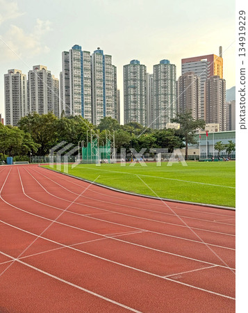 Urban running track and green field with tall apartment buildings in the background Urban running track and green field with tall apartment buildings in the background 134919229