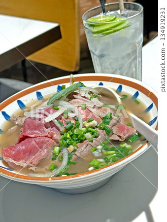 Delicious beef pho noodle soup with fresh ingredients and a refreshing drink Delicious beef pho noodle soup with fresh ingredients and a refreshing drink 134919231