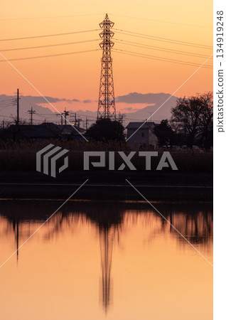 Isanuma Lake bathed in the evening light and the silhouette of a power transmission tower reflected on the water's surface 134919248