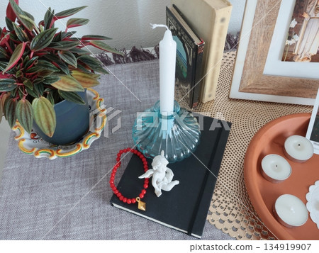 Catholic believer corner at home. Icons and candles. Angel figurine and bracelet. Faith, symbols, and traditions. 134919907