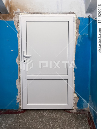 White door in an unfinished wall in a blue-painted room. 134920048